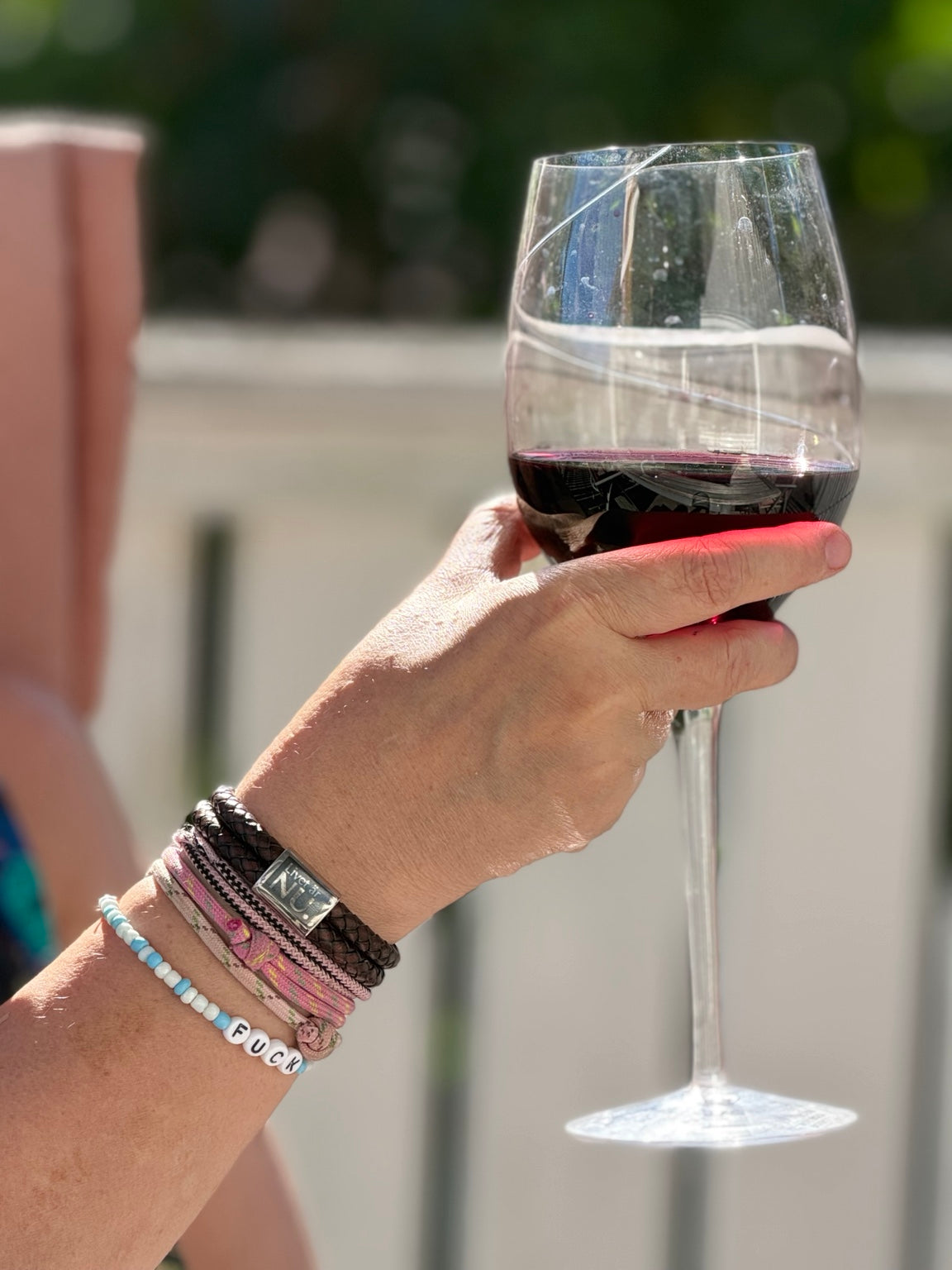 Livet är nu-armband på handled i varmt kvällsljus med vinglas i bakgrunden