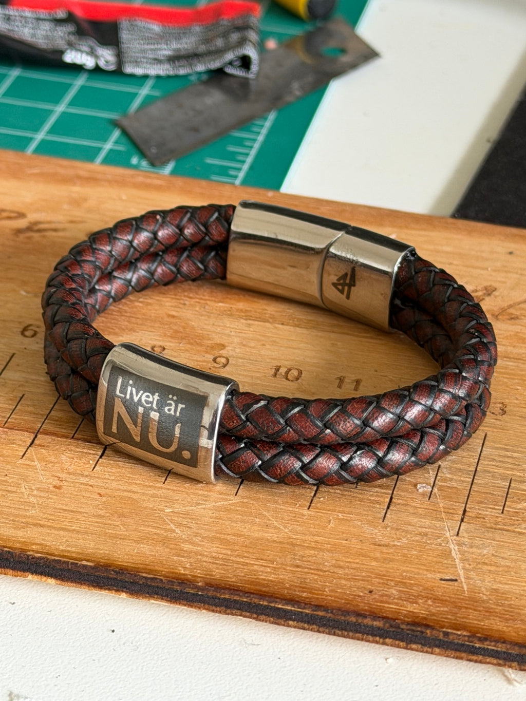 Handgjort Livet är nu armband på arbetsbänk med brun läderrem och graverad pärla
