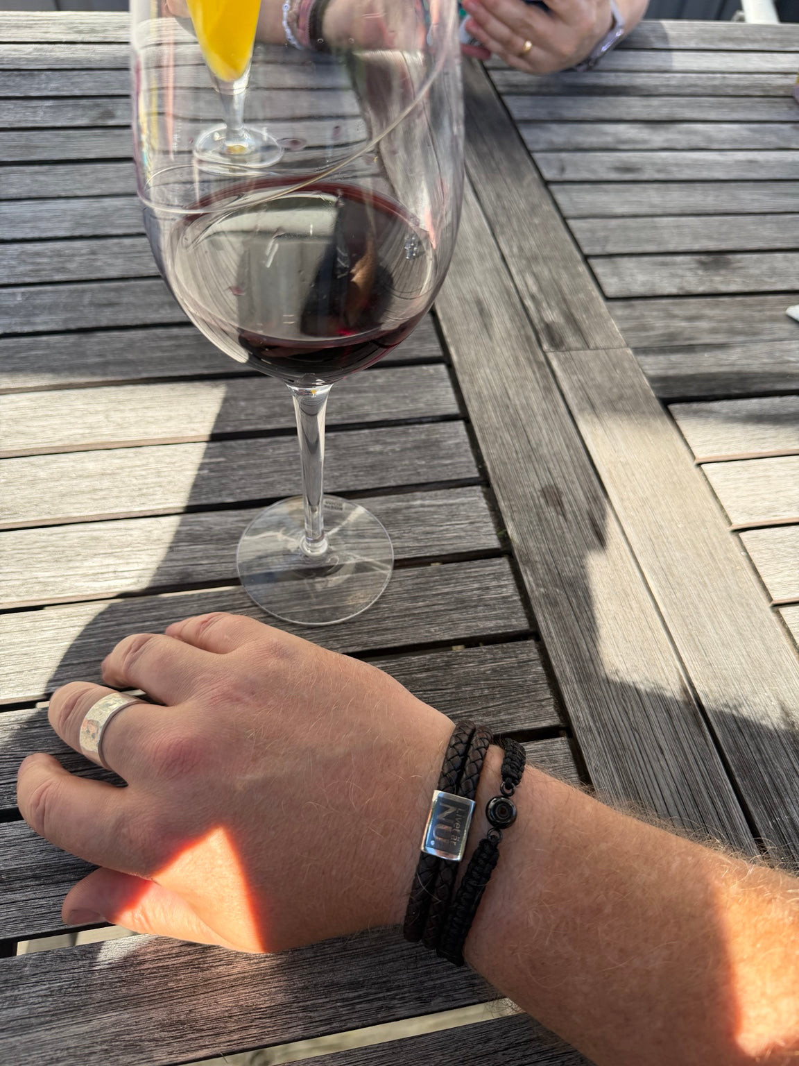Livet är nu armband på handled vid ett bord med vinglas